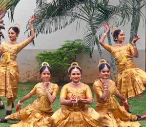 Dancers in gold costumes posing on a lawn